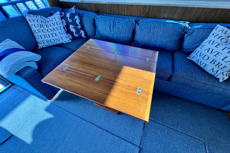 Live Wire Yacht Photos Pics Cozy interior of 1982 Bertram 46 Convertible with wooden table and blue sofa.