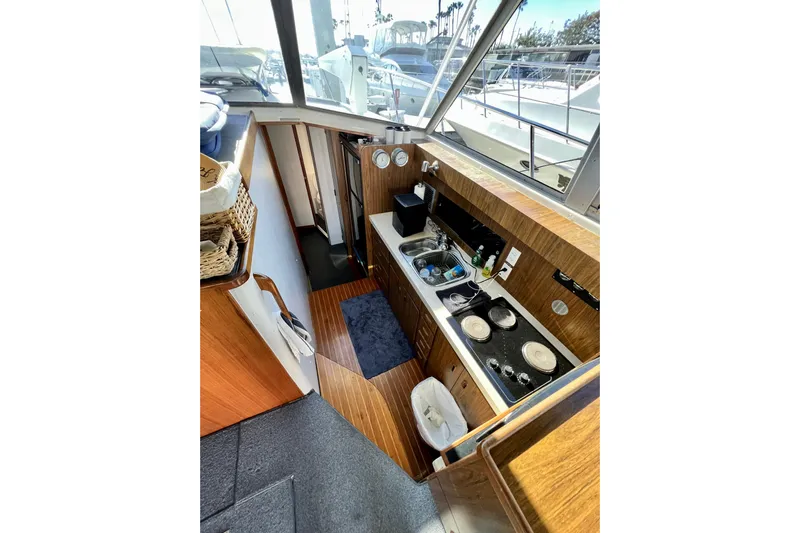 Live Wire Yacht Photos Pics Interior of 1982 Bertram 46 Convertible yacht, featuring compact kitchen with stove and sink.