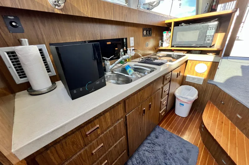 Live Wire Yacht Photos Pics 1982 Bertram 46 Convertible yacht kitchen with wood cabinetry, sink, and microwave.