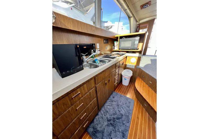 Live Wire Yacht Photos Pics Interior of 1982 Bertram 46 Convertible yacht kitchen with wood cabinetry and modern appliances.