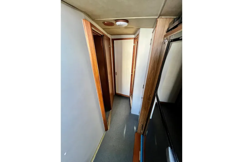 Live Wire Yacht Photos Pics Narrow hallway inside 1982 Bertram 46 Convertible yacht with wooden doors and carpeted floor.