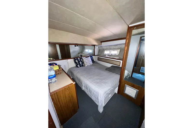Live Wire Yacht Photos Pics 1982 Bertram 46 Convertible cabin interior with bed, wooden cabinetry, and nautical decor.