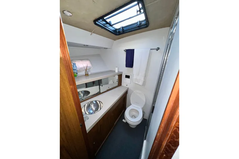 Live Wire Yacht Photos Pics Bathroom interior of 1982 Bertram 46 Convertible yacht, featuring sink, toilet, and skylight.