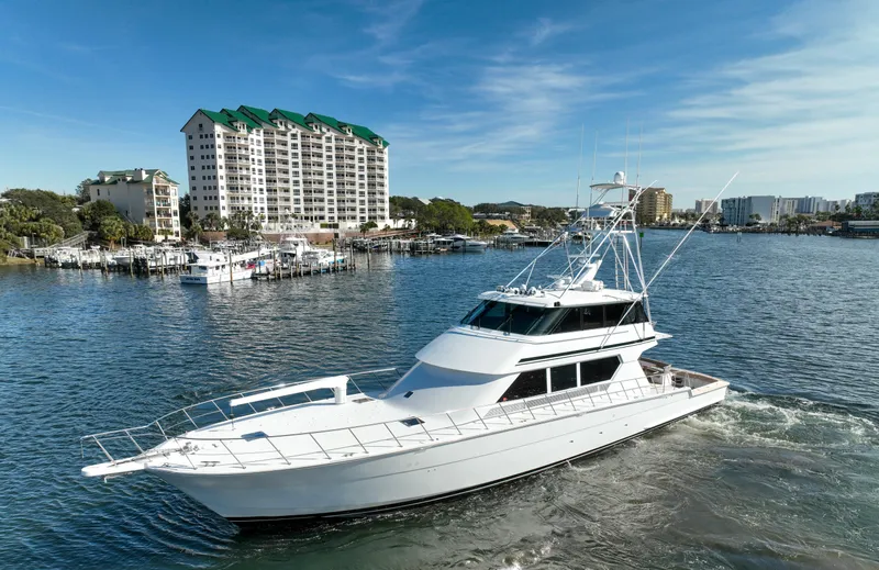 Pole Position Yacht Photos Pics 1997 Hatteras Sportfish yacht cruising in a marina with waterfront buildings.