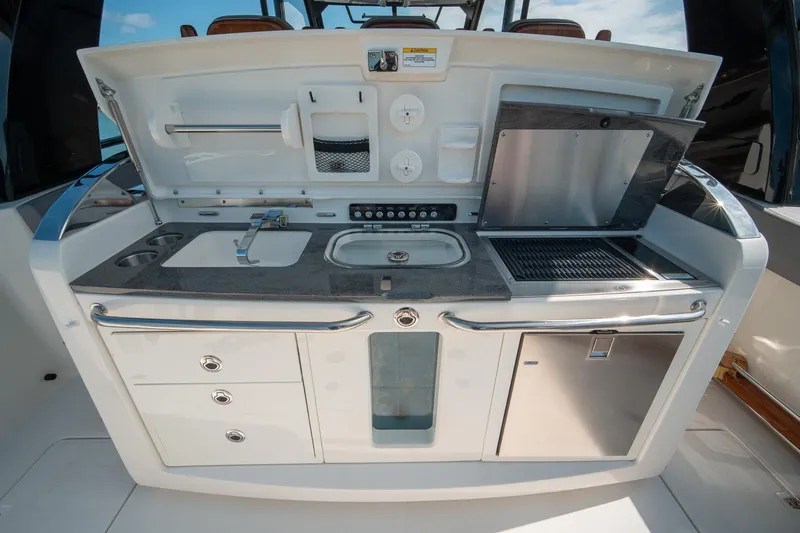 Pipe Dream Yacht Photos Pics 2023 Boston Whaler 420 Outrage boat kitchen with sink, grill, and storage compartments.