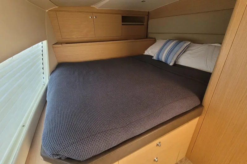  Yacht Photos Pics Cozy cabin bed in 2025 Makai M37 yacht with wooden cabinetry and striped pillow.