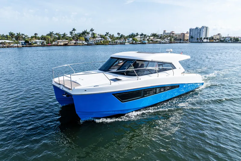  Yacht Photos Pics 2025 Makai M37 boat cruising on a sunny day near a coastal city.