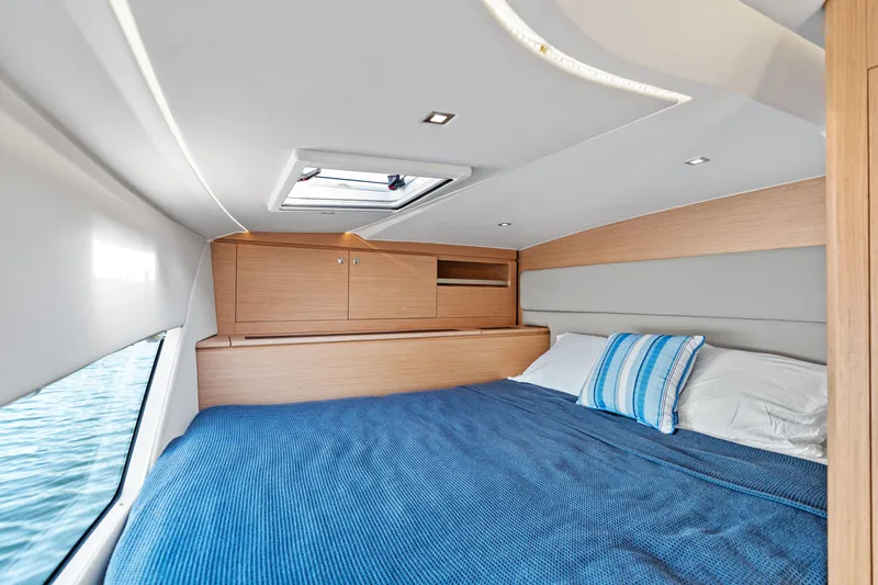  Yacht Photos Pics Luxurious cabin interior of 2025 Makai M37 yacht with cozy bedding and wooden cabinetry.