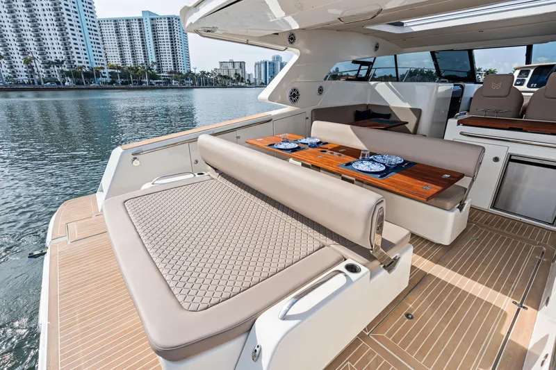  Yacht Photos Pics Luxurious 2025 Makai M37 yacht interior with elegant seating and dining area, docked by waterfront buildings.