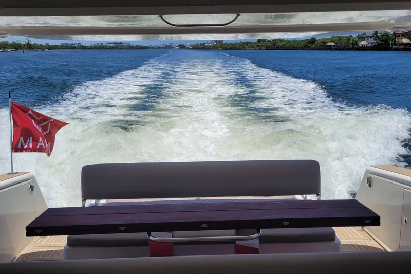  Yacht Photos Pics Wake view from a 2025 Makai M37 boat, featuring a red flag and serene waters.