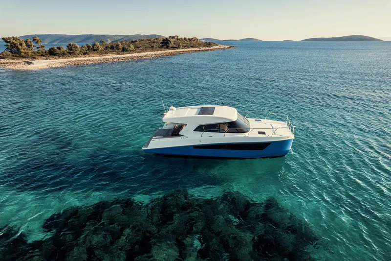  Yacht Photos Pics 2025 Makai M37 yacht cruising in clear blue waters near a scenic coastline.