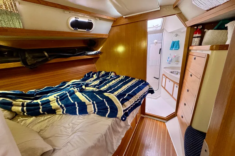 Ostrich Yacht Photos Pics Cozy cabin interior of 2004 Catalina 42 MkII sailboat with striped bedding and wooden finishes.
