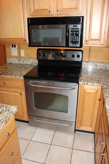  Yacht Photos Pics Modern kitchen with stainless steel oven and microwave, granite countertops, wooden cabinets.