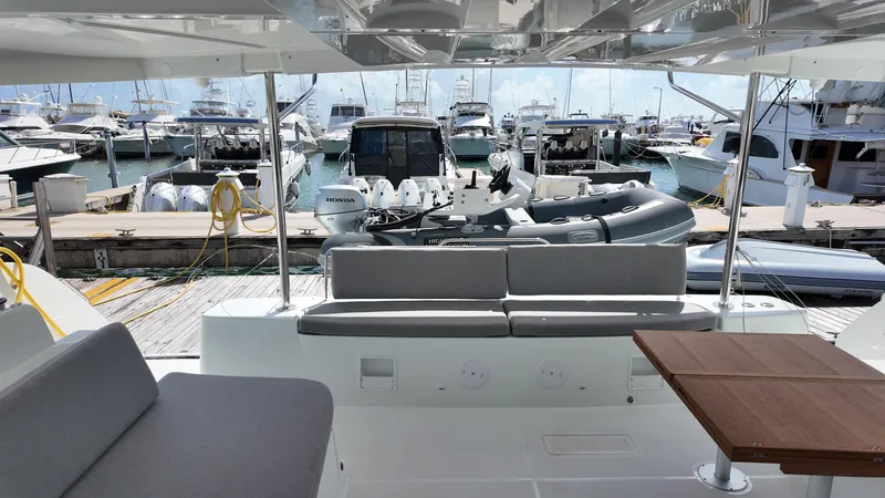  Yacht Photos Pics 2025 Lagoon 46 yacht interior with marina view, featuring seating and a wooden table.