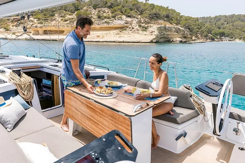  Yacht Photos Pics Couple enjoying a meal on a 2026 Dufour 41 yacht, anchored in a scenic bay.