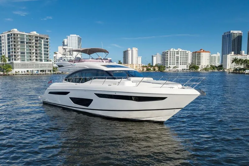 Above Deck Yacht Photos Pics 2018 Princess S60 yacht cruising near modern waterfront buildings under clear blue sky.