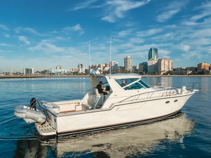 Miss Michelle Yacht Photos Pics 1996 Tiara Yachts 4300 cruising on calm water with city skyline backdrop.