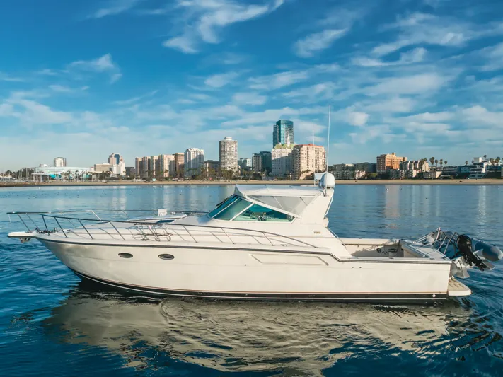 Miss Michelle Yacht Photos Pics 1996 Tiara Yachts 4300 cruising on calm waters with city skyline backdrop.