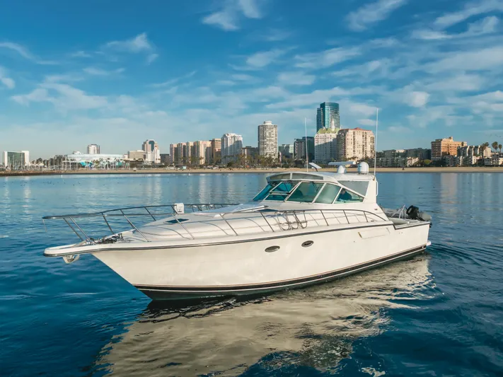 Miss Michelle Yacht Photos Pics 1996 Tiara Yachts 4300 cruising on calm waters with city skyline backdrop.