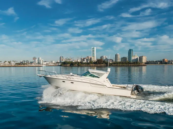 Miss Michelle Yacht Photos Pics 1996 Tiara Yachts 4300 cruising on calm waters with city skyline backdrop.