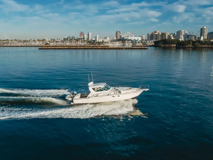 Miss Michelle Yacht Photos Pics 1996 Tiara Yachts 4300 cruising on calm waters with city skyline in background.