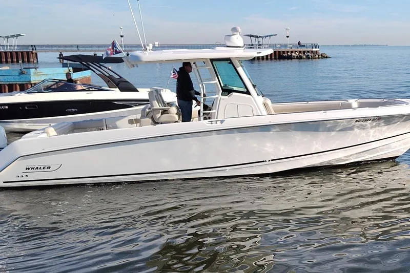  Yacht Photos Pics 2019 Boston Whaler 330 Outrage boat cruising on calm water near a pier.