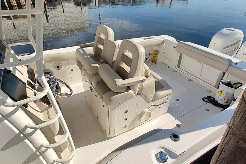  Yacht Photos Pics 2019 Boston Whaler 330 Outrage boat interior with dual seats and steering wheel, docked by water.