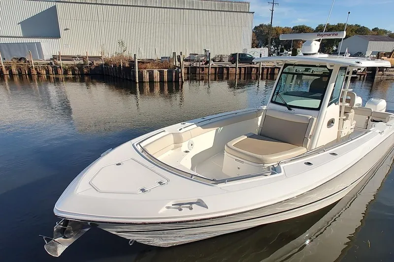  Yacht Photos Pics 2019 Boston Whaler 330 Outrage boat docked in calm waters, featuring sleek design and modern amenities.