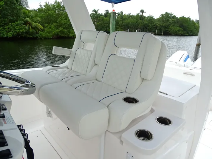  Yacht Photos Pics Luxurious seating on 2022 Intrepid 407 Panacea boat with cup holders, near lush greenery.