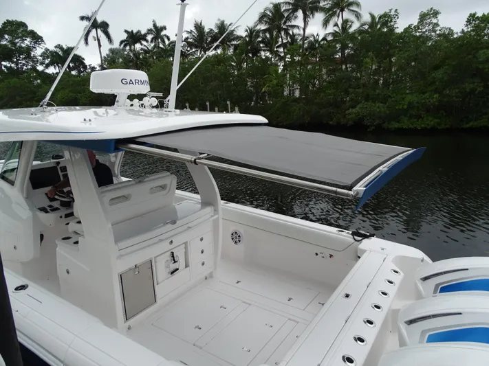  Yacht Photos Pics 2022 Intrepid 407 Panacea boat with canopy, docked near lush greenery.