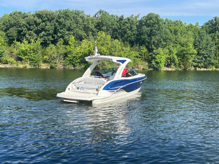  Yacht Photos Pics 2023 Formula 310 Bowrider I/O cruising on a serene lake with lush green trees.
