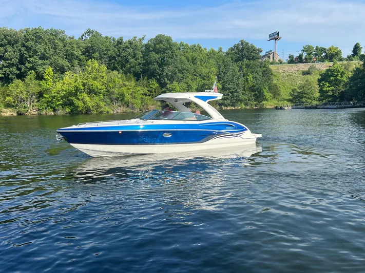  Yacht Photos Pics 2023 Formula 310 Bowrider I/O boat cruising on a scenic lake with lush green trees.