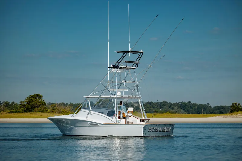 Nuts And Bolts Yacht Photos Pics 1998 Scopinich Custom Express boat on calm water with fishing rods.