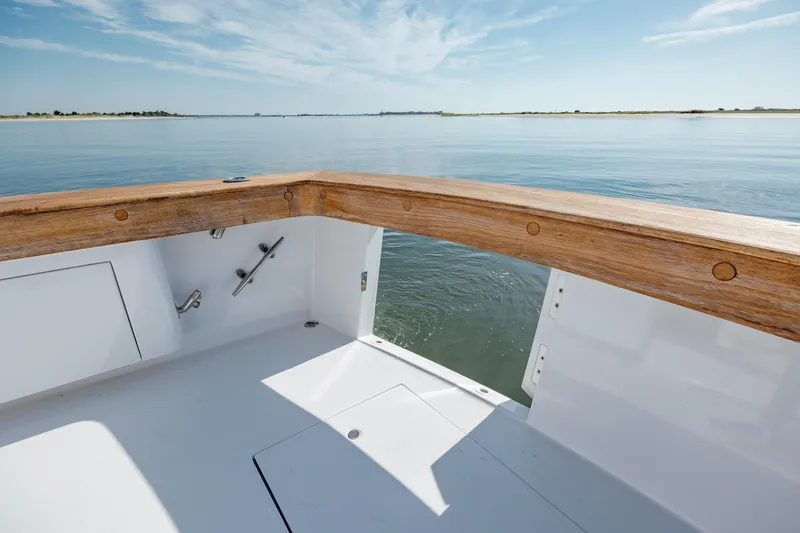 Nuts And Bolts Yacht Photos Pics 1998 Scopinich Custom Express boat deck with wooden railing on calm water.