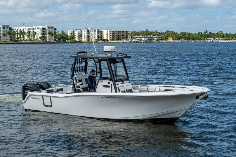 Floating Stones Yacht Photos Pics 2022 Tidewater 292 CC Adventure boat cruising on a sunny day near waterfront buildings.