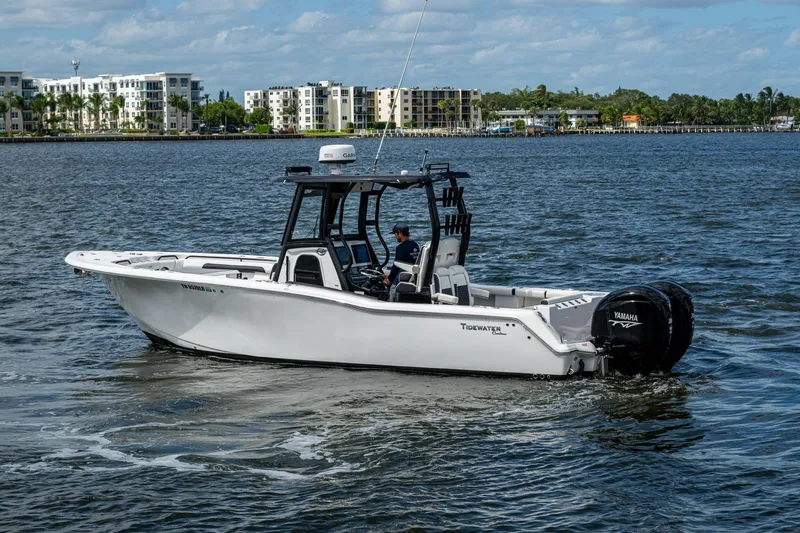 Floating Stones Yacht Photos Pics 2022 Tidewater 292 CC Adventure boat cruising on a scenic waterfront with modern buildings.