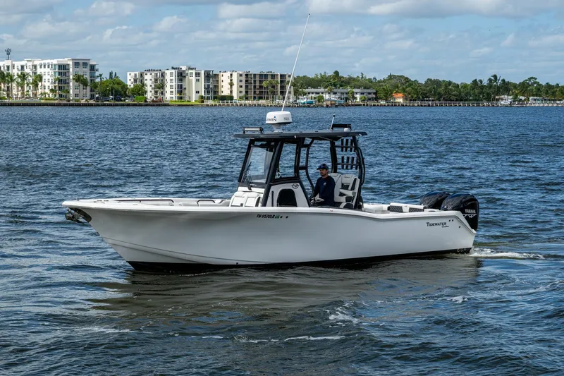 Floating Stones Yacht Photos Pics 2022 Tidewater 292 CC Adventure boat cruising on a sunny day near waterfront buildings.