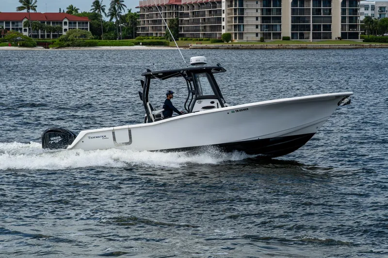 Floating Stones Yacht Photos Pics 2022 Tidewater 292 CC Adventure boat cruising on water near waterfront buildings.