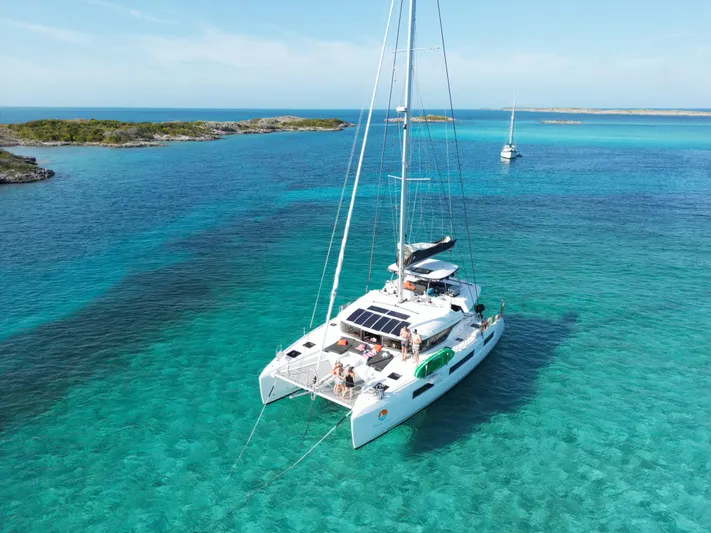 Buena Vida Yacht Photos Pics 2023 Lagoon 50 catamaran sailing in clear turquoise waters near small islands.