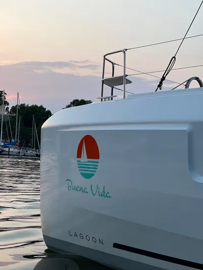Buena Vida Yacht Photos Pics 2023 Lagoon 50 catamaran "Buena Vida" docked at sunset with scenic background.