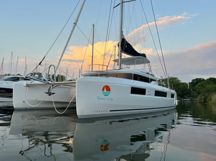 Buena Vida Yacht Photos Pics 2023 Lagoon 50 catamaran on calm water at sunset, showcasing sleek design and modern features.