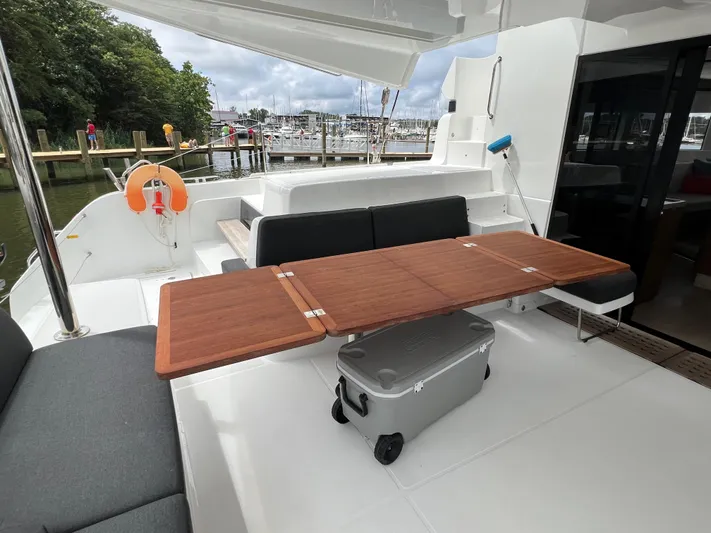 Buena Vida Yacht Photos Pics 2023 Lagoon 50 yacht deck with wooden table, seating, and marina view.