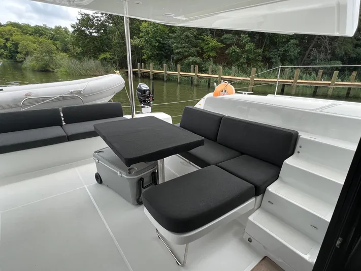 Buena Vida Yacht Photos Pics 2023 Lagoon 50 yacht with sleek seating area and table, docked by a serene waterfront.