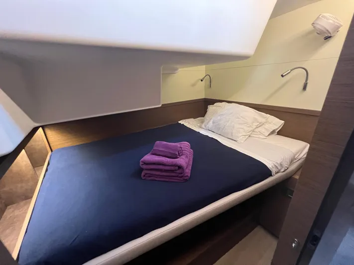 Buena Vida Yacht Photos Pics Cozy cabin interior of 2023 Lagoon 50 yacht with bed and purple towels.