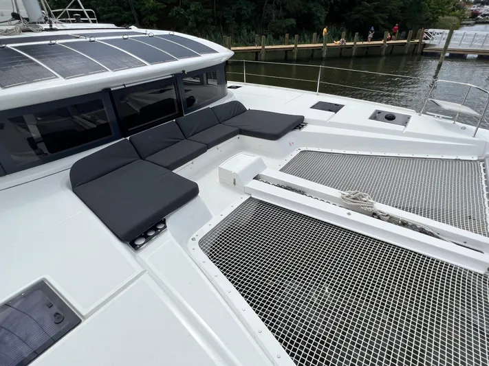 Buena Vida Yacht Photos Pics 2023 Lagoon 50 catamaran with spacious deck and seating area, docked by the water.