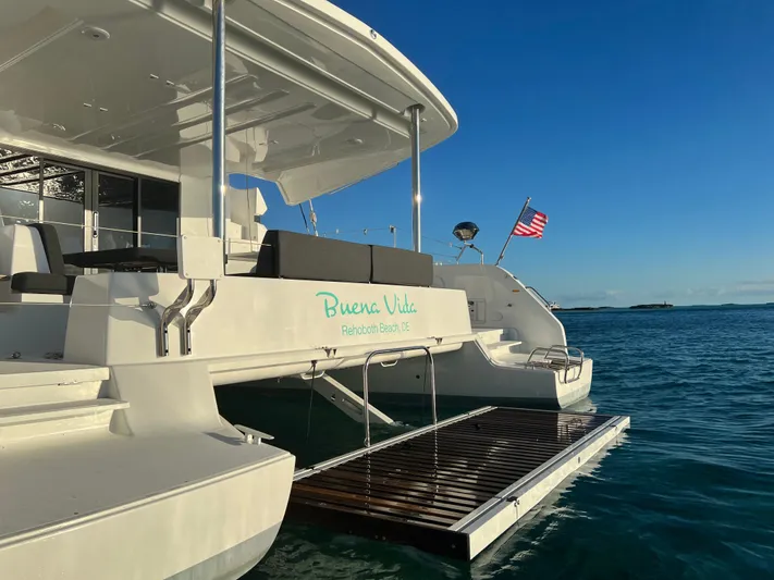 Buena Vida Yacht Photos Pics 2023 Lagoon 50 catamaran on water, American flag, sunny day, rear view.