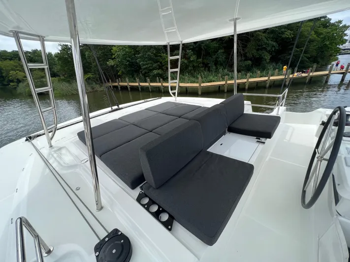 Buena Vida Yacht Photos Pics Luxurious 2023 Lagoon 50 catamaran deck with comfortable seating, docked by a scenic waterfront.
