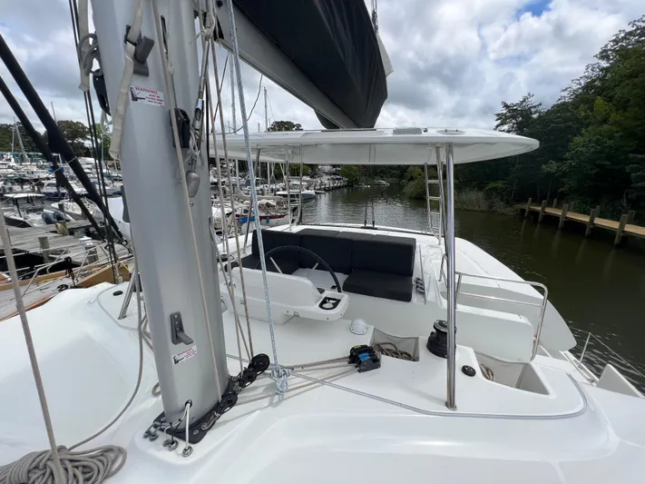 Buena Vida Yacht Photos Pics 2023 Lagoon 50 catamaran helm station with seating, docked at a marina under cloudy skies.