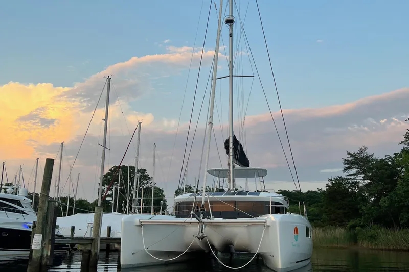 Buena Vida Yacht Photos Pics 2023 Lagoon 50 catamaran docked at sunset with colorful sky and trees in the background.