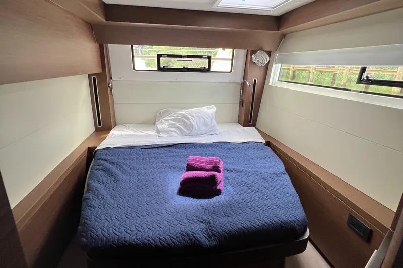 Buena Vida Yacht Photos Pics 2023 Lagoon 50 yacht cabin with bed, blue bedding, and window view.